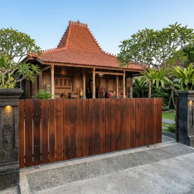 Pagar kayu ulin minimalis modern dari bekas bantalan lori yang melindungi rumah tradisional Joglo dengan estetika mewah.